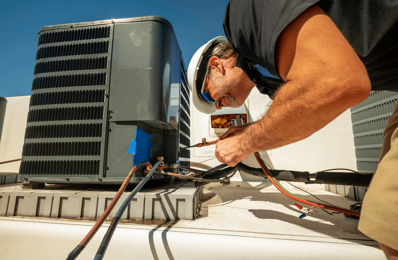 RSK Technical engineer repairing and servicing rooftop HVAC packaged unit on commercial building rooftop Dubai UAE